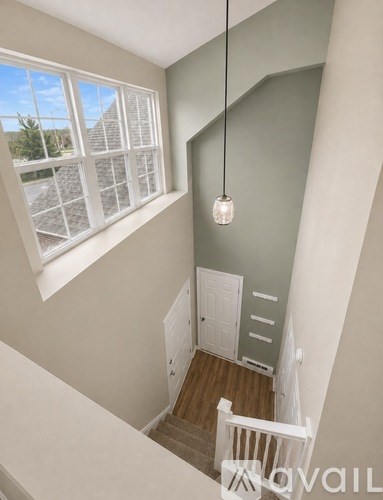 A white door is in a hallway with a light hanging from the ceiling.