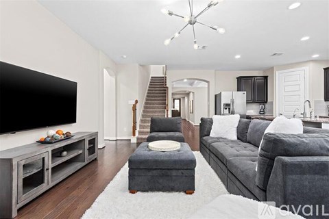 A modern living room with a grey couch and a television on a cabinet.
