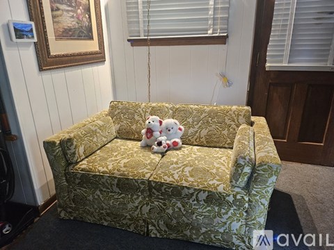 A green couch with a teddy bear on it.