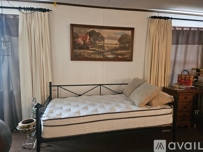 A bedroom with a large bed and a painting on the wall.