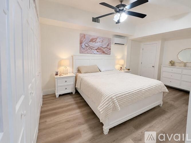 A bedroom with a large bed, a dresser, and a ceiling fan.