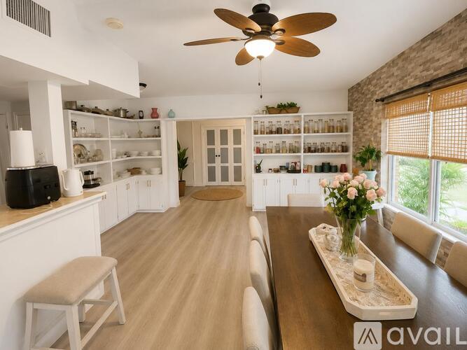 A well-lit kitchen with a ceiling fan and a dining table with chairs.