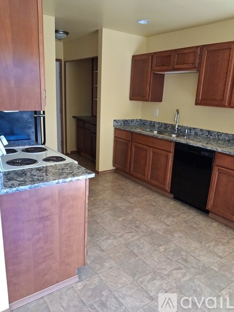 A kitchen with wooden cabinets and a granite countertop.