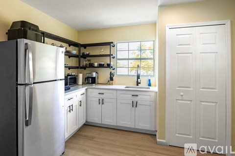 A kitchen with a white refrigerator and cabinets.