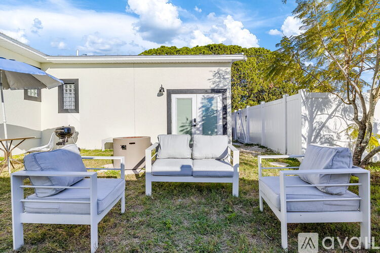A white patio furniture set is set up on a grassy area in front of a house.