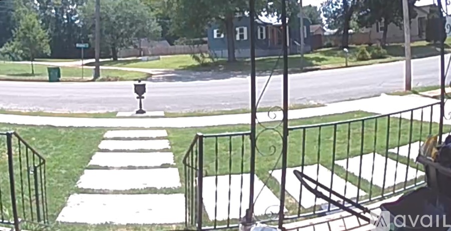 A black metal fence with a white gate is in front of a green lawn.