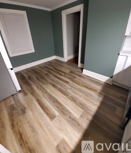 A room with wooden flooring and a window with blinds.
