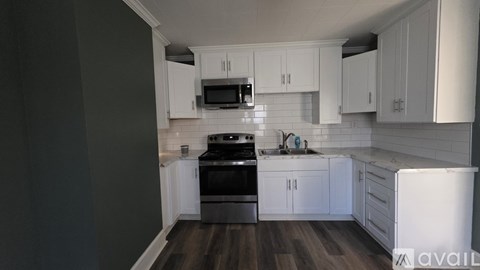 A kitchen with white cabinets and a black stove top oven.
