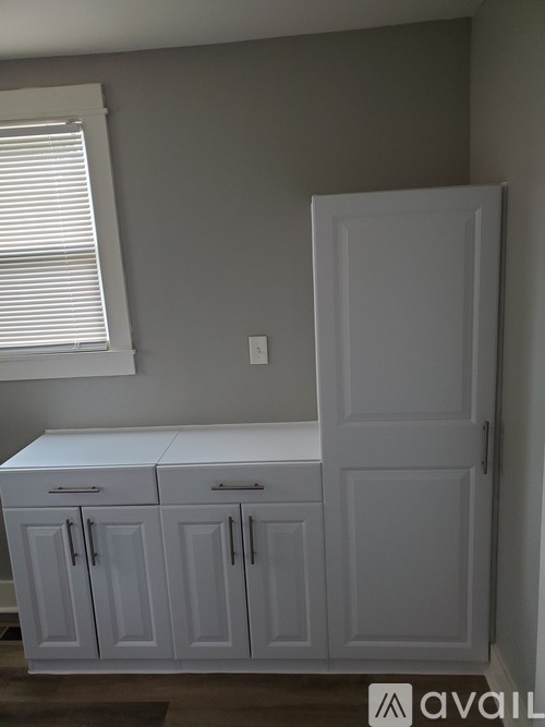 A white cabinet with a white countertop and a white door is in a room.