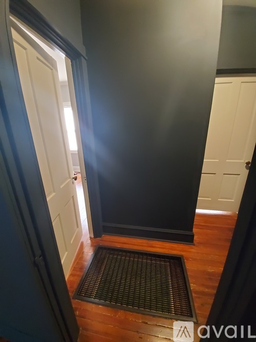 A hallway with a black wall and a white door.