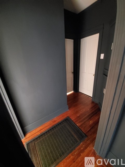 A hallway with a wooden floor and a white door.