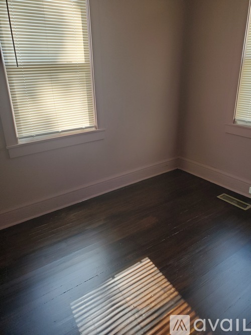 A room with wooden floors and a window with blinds.