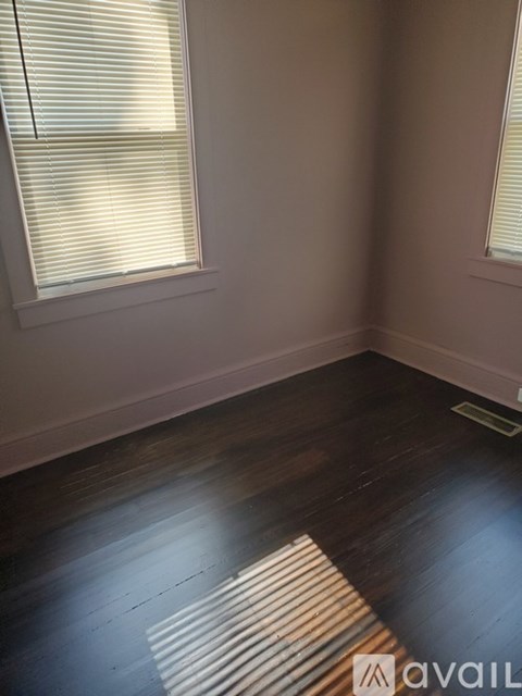A room with wooden floors and a window with blinds.