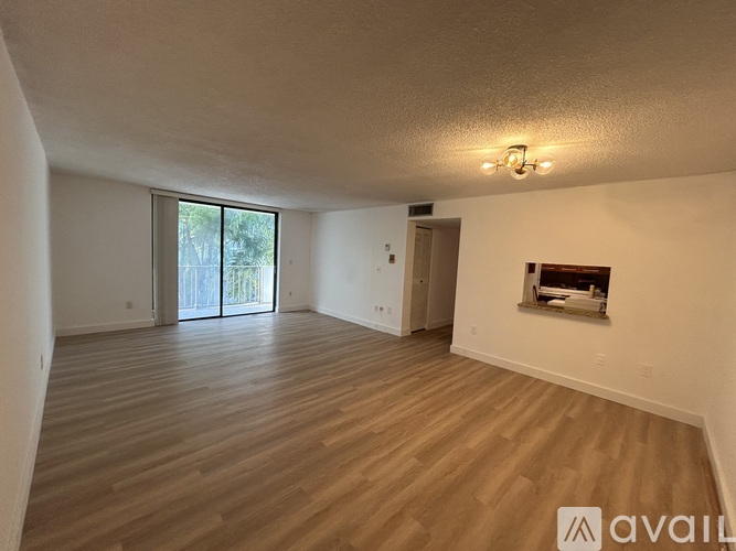 A spacious room with wooden flooring and a sliding glass door leading outside.