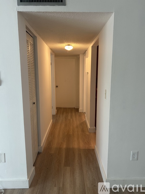 A long hallway with wood floors and white walls.