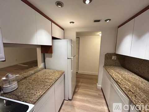 A kitchen with white cabinets and a granite countertop.