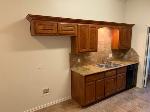 A kitchen with brown cabinets and a granite countertop.