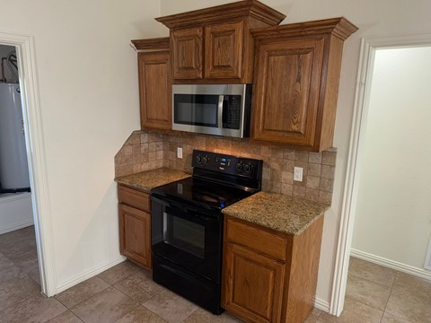 A kitchen with wooden cabinets and black appliances.