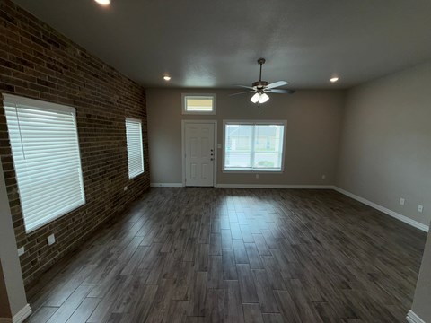 A room with a ceiling fan and wooden flooring.