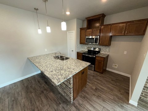 A kitchen with granite countertops and wooden cabinets.