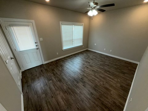 A room with a ceiling fan and wooden flooring.