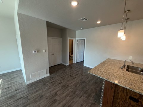 A kitchen with a granite countertop and wooden flooring.