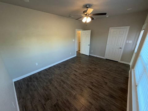 A room with wooden flooring and a ceiling fan.