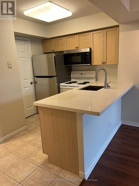 A kitchen with a white counter top and wooden cabinets.