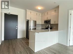 A kitchen with white cabinets and a black door.