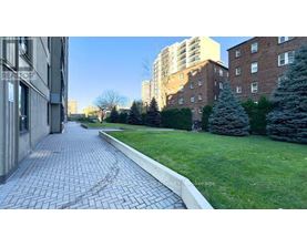 A brick pathway leads through a grassy area between two buildings.