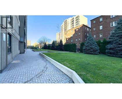 A brick pathway leads through a grassy area between two buildings.