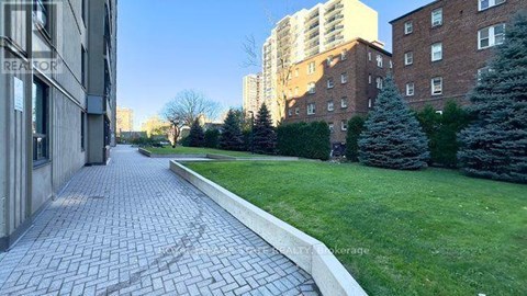 A brick pathway leads through a grassy area between two buildings.