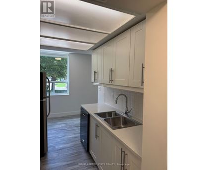 A kitchen with white cabinets and a black refrigerator.