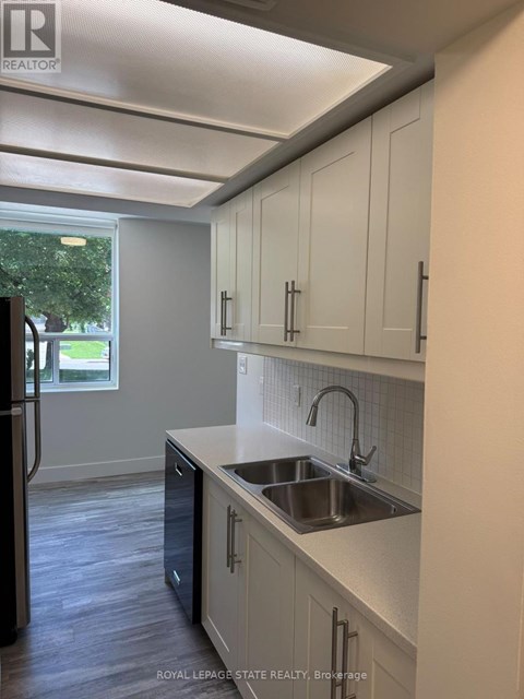 A kitchen with white cabinets and a black refrigerator.