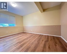 A room with wooden flooring and a window with blinds.