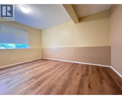 A room with wooden flooring and a window with blinds.