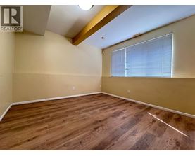 A room with wooden flooring and a window with blinds.
