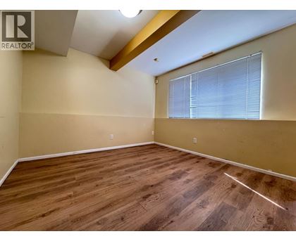 A room with wooden flooring and a window with blinds.
