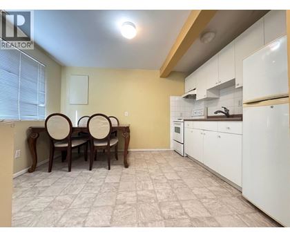 A kitchen with white cabinets and a dining table with chairs.