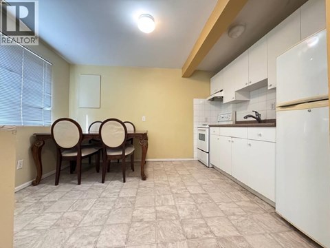 A kitchen with white cabinets and a dining table with chairs.