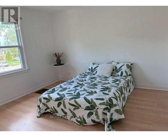 A bedroom with a bed covered in a green leaf print bedspread.