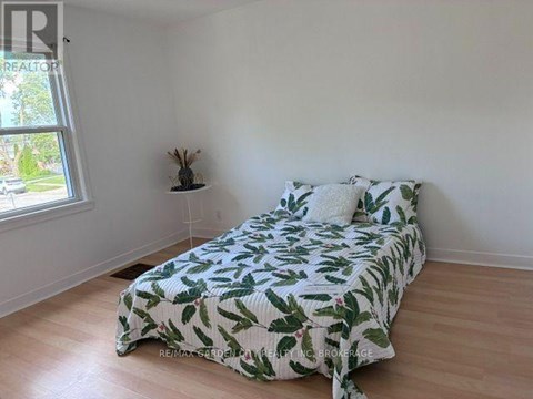 A bedroom with a bed covered in a green leaf print bedspread.