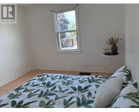 A bedroom with a bed, a window, and a wall-mounted shelf.
