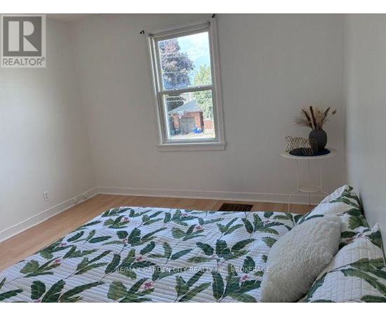 A bedroom with a bed, a window, and a wall-mounted shelf.
