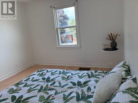 A bedroom with a bed, a window, and a wall-mounted shelf.