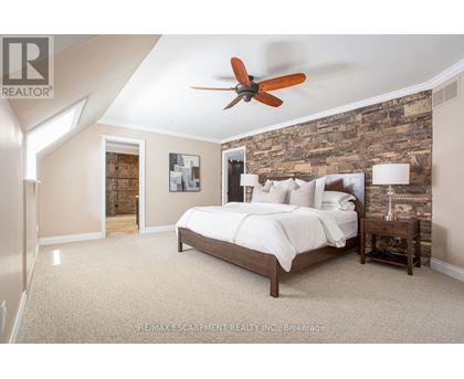 A bedroom with a bed, nightstand, and a ceiling fan.