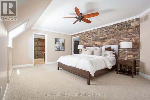 A bedroom with a bed, nightstand, and a ceiling fan.
