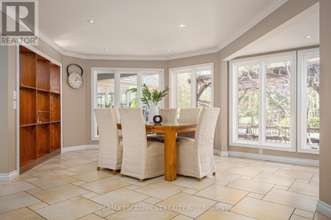A dining room with a table and chairs and a clock on the wall.