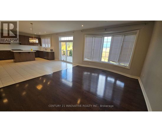 A spacious room with wooden floors and a large window with blinds.
