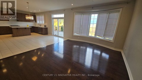 A spacious room with wooden floors and a large window with blinds.
